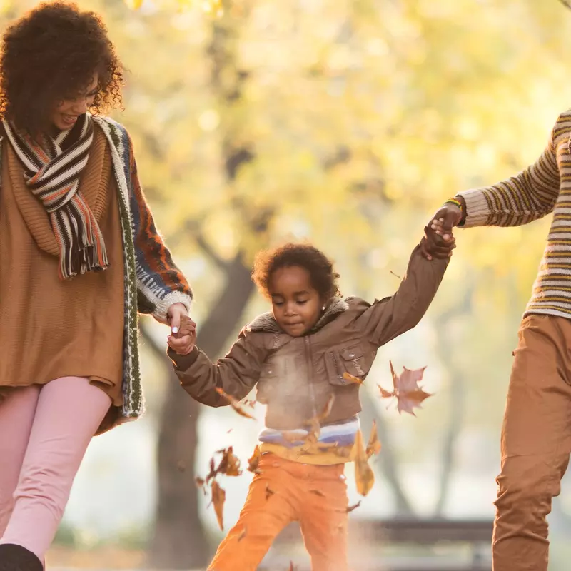 A family walking outside in the fall. 