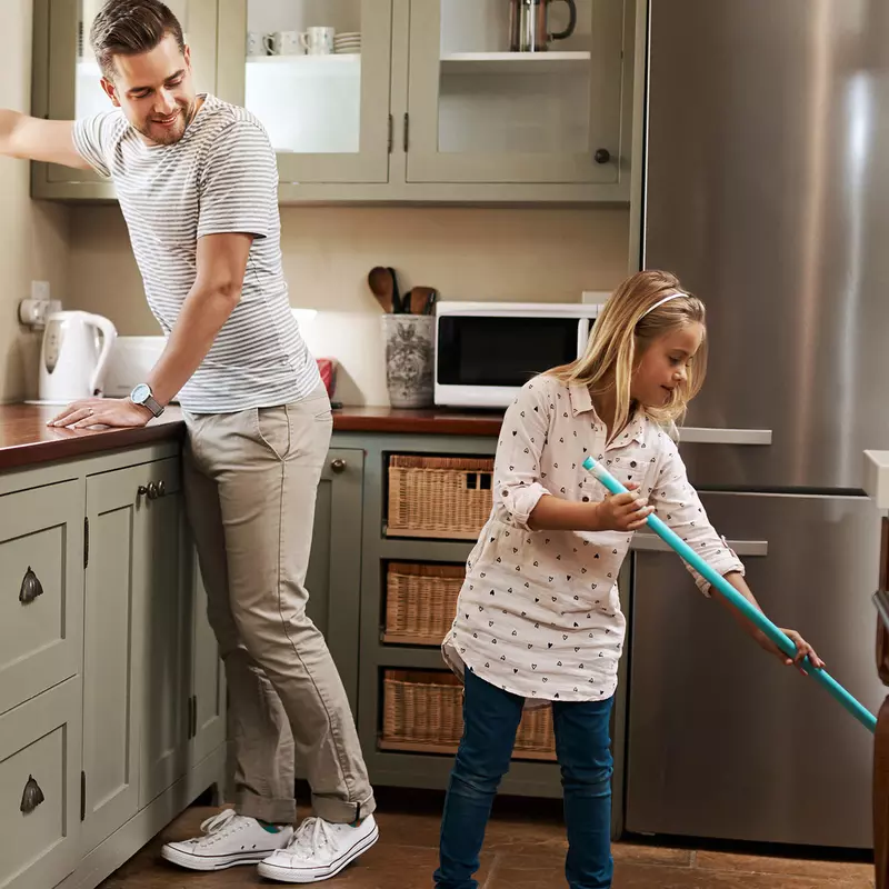 A father and his young daughter clean the kitchen