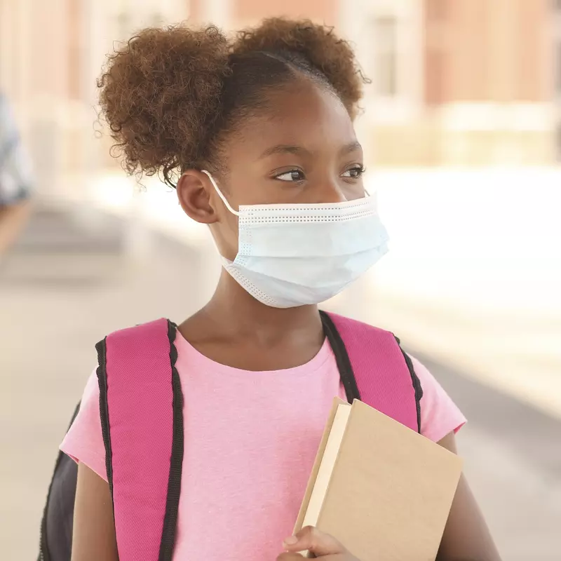 A girl attending school and wearing a mask. 