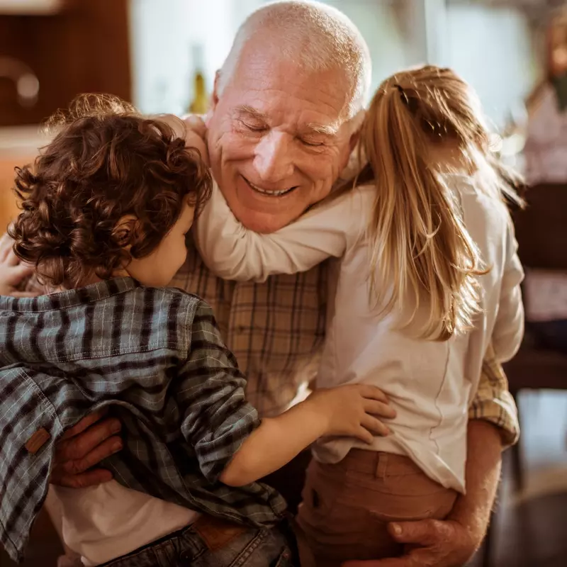 A grandfather hugs his grandchildren.
