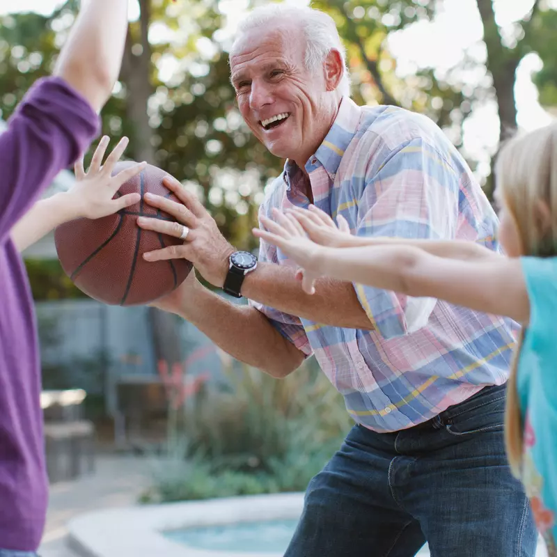 A grandfather plays basketball with his granddaughters. 