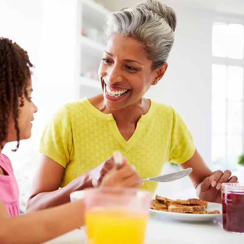 A grandmother and granddaughter eating breakfast together.