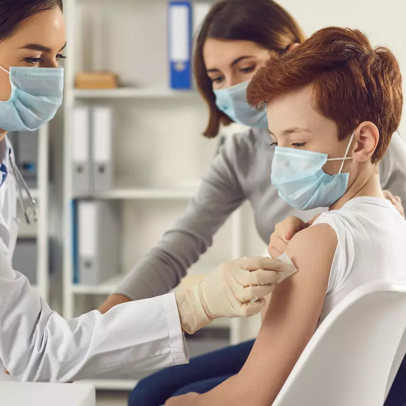 A teenager getting a vaccine shot by a doctor