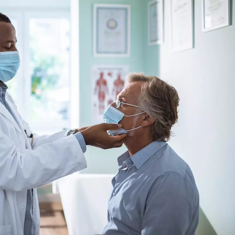 A Doctor Examines a Patient's Throat While Taking Vitals
