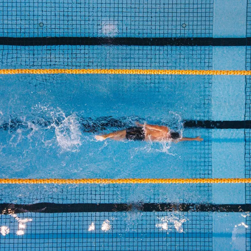 An olympic swimmer paddles freestyle through the water