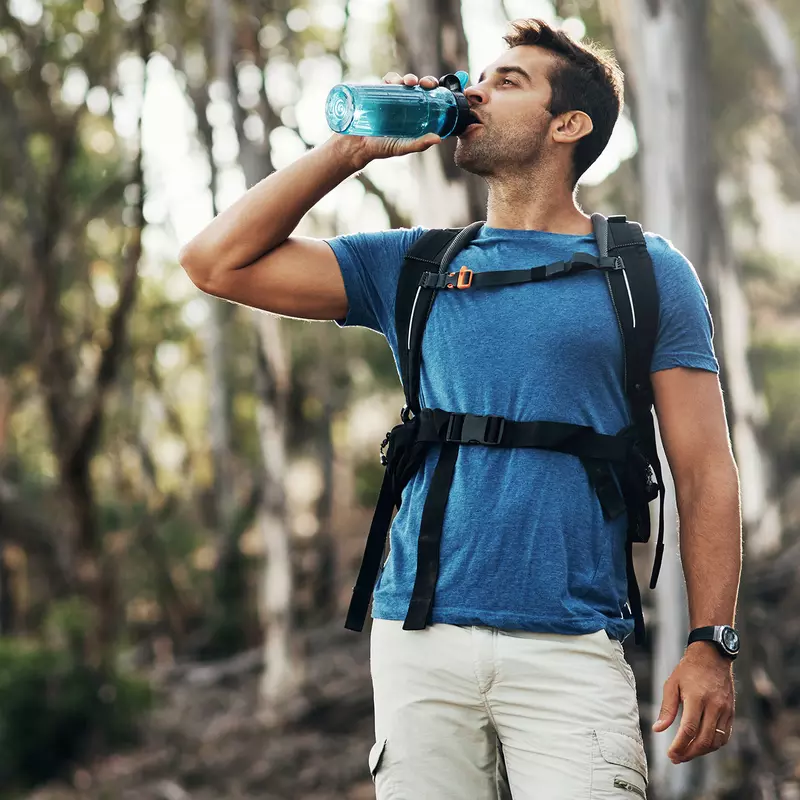 A man drinking water on a hike.