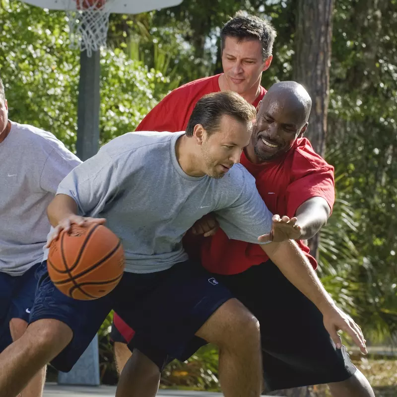 A group of men play basketball.