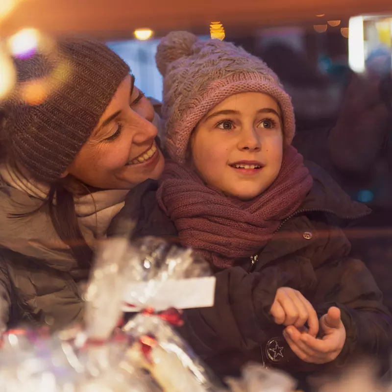 A mother and child looking at holiday storefronts. 