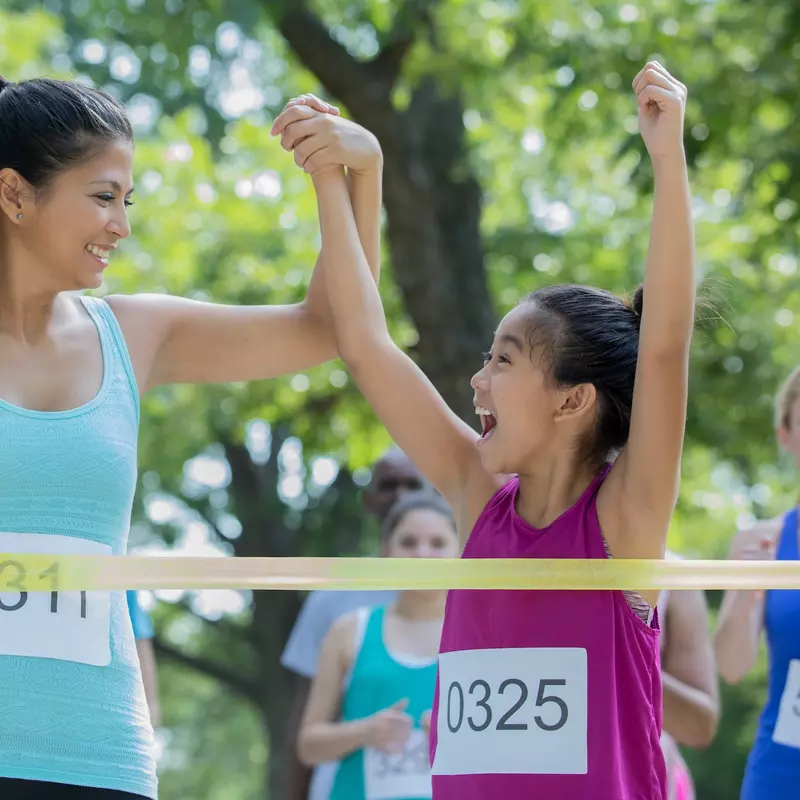 A mom and daughter cross the finish line at a 5k together.