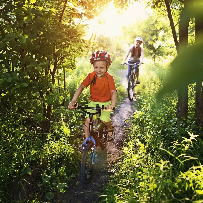 A boy races his bike ahead of his mom on the trail