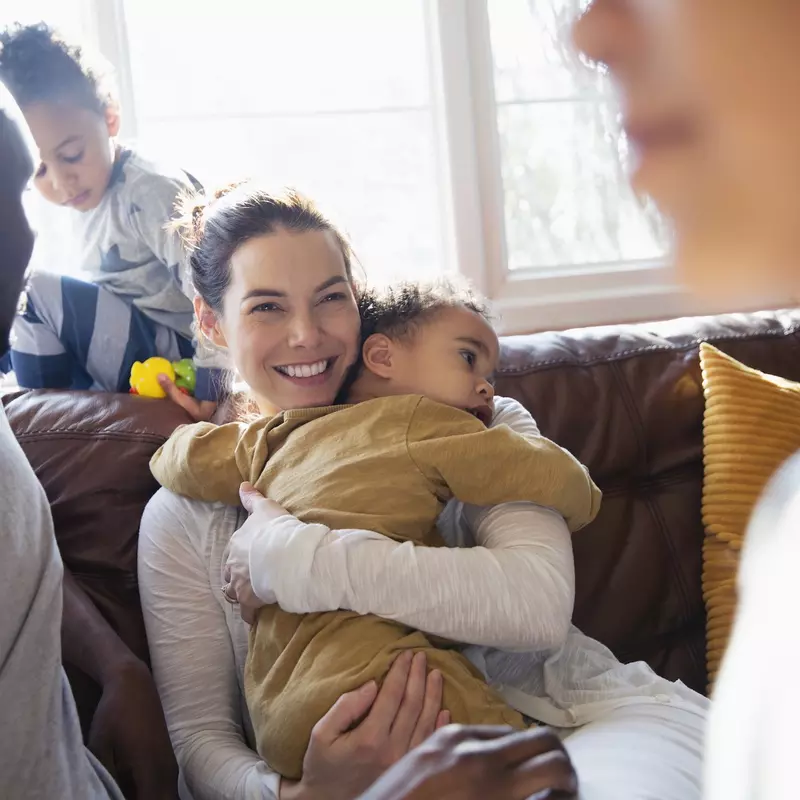 Woman holding child while sitting with family