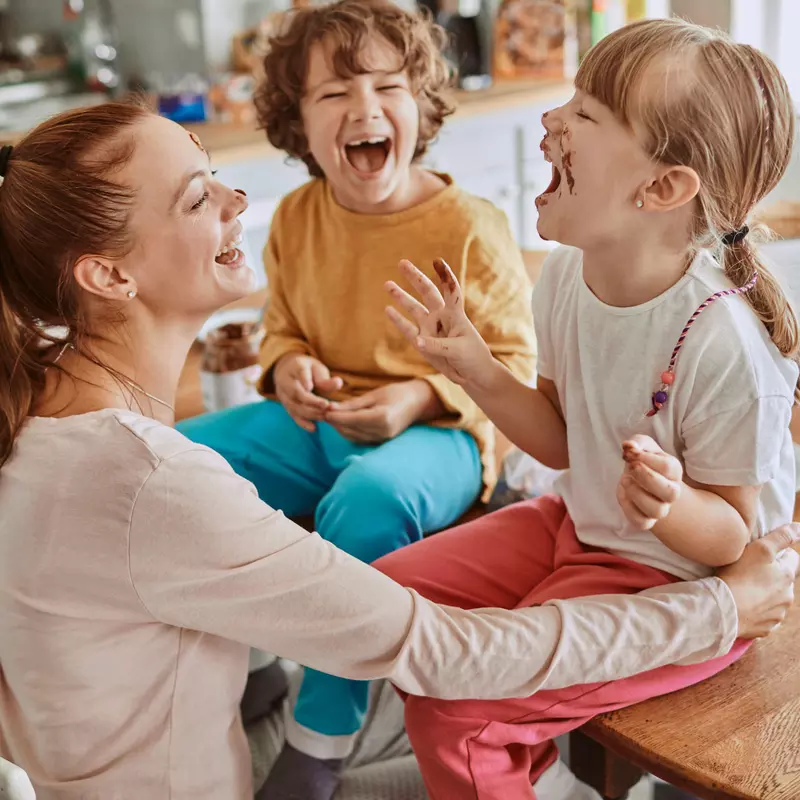 A mom laughs her way through a messy lunch with her kids.