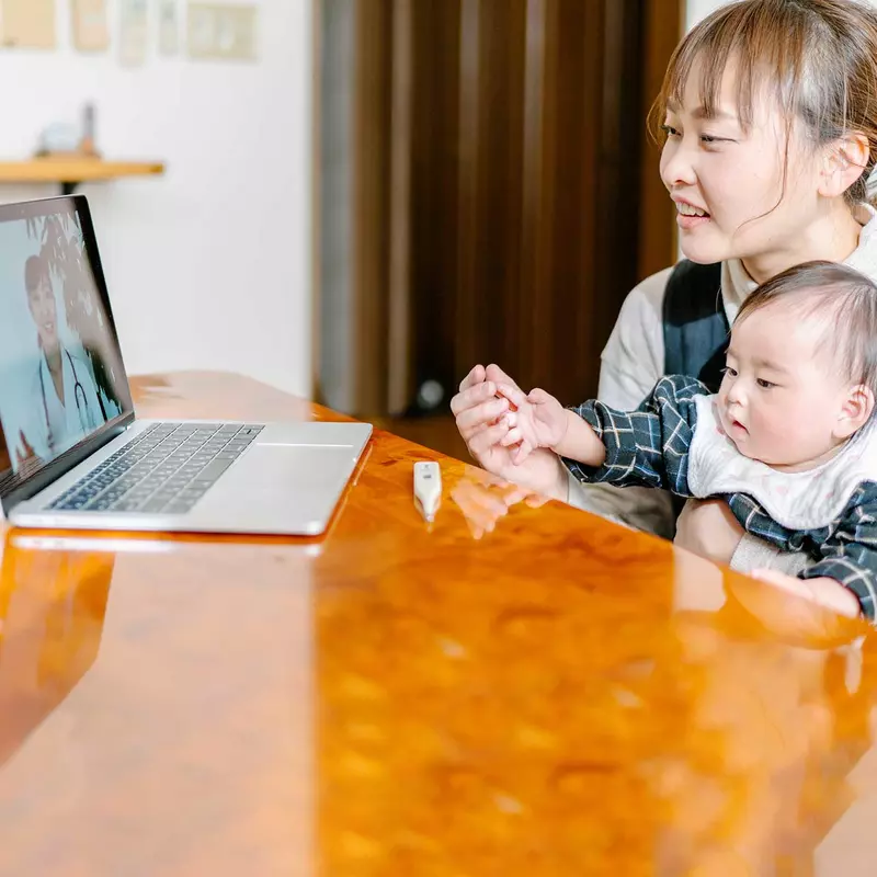 A mom has a video chat with her doctor and infant. 