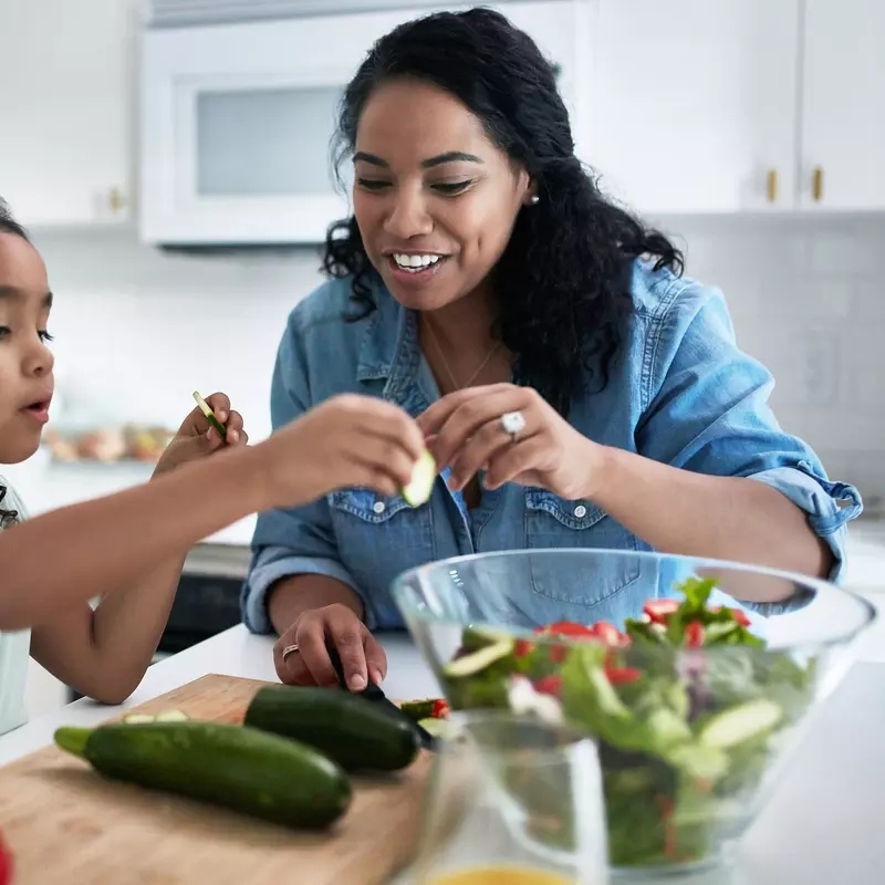 A mother and daughter making a salad together.