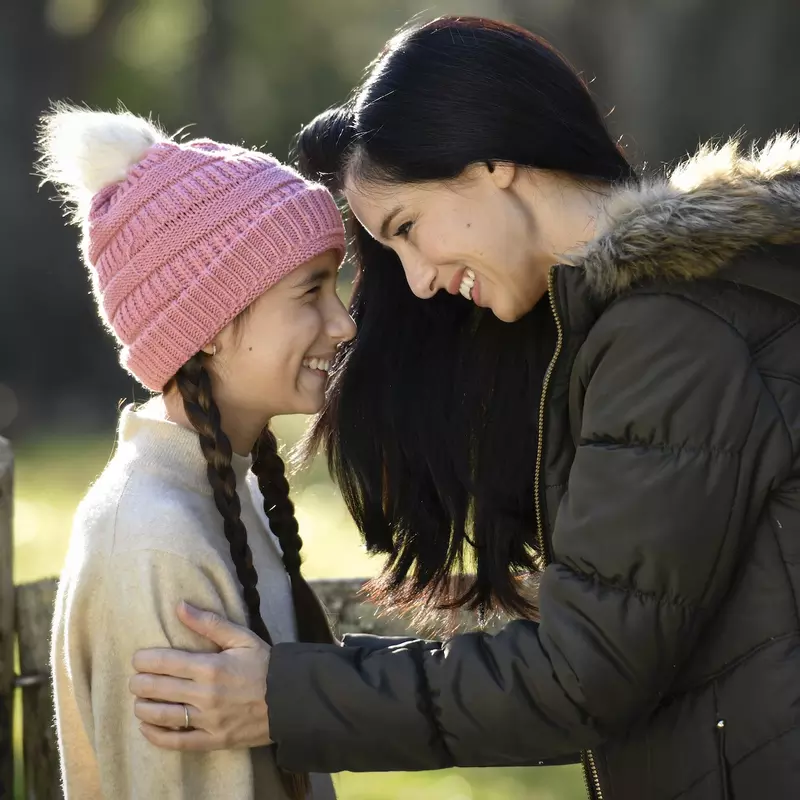 A mother and daughter smiling while outdoors.