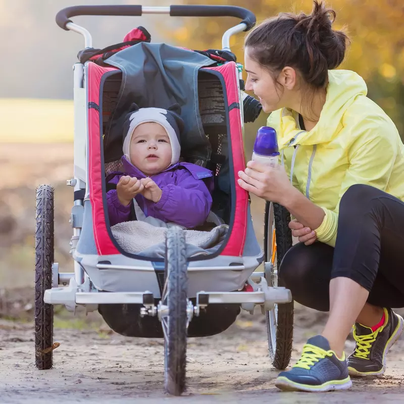 A new mom takes a water break during a run with her baby.
