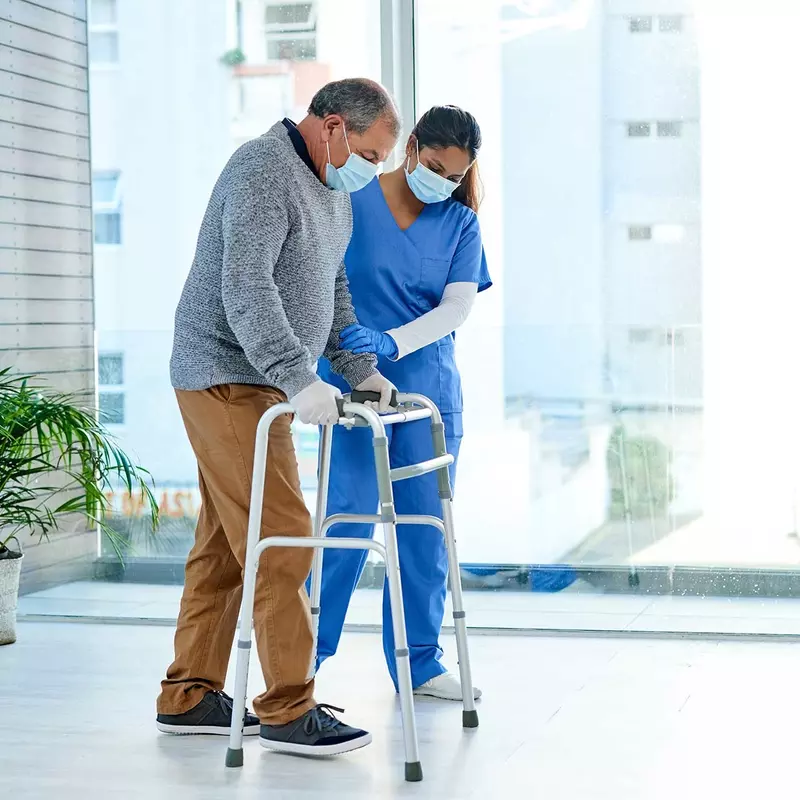 A nurse assisting a senior man while using a walker