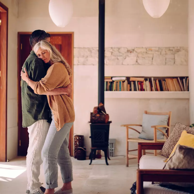 A mature man and woman embrace in their living room