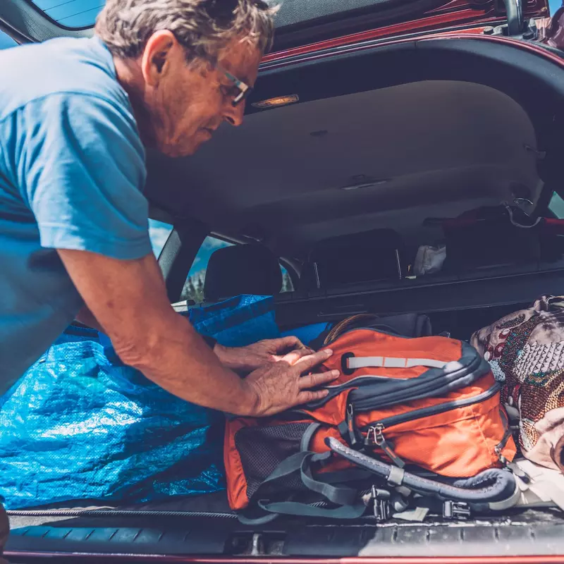 A man packs his belongings in the trunk of his car.
