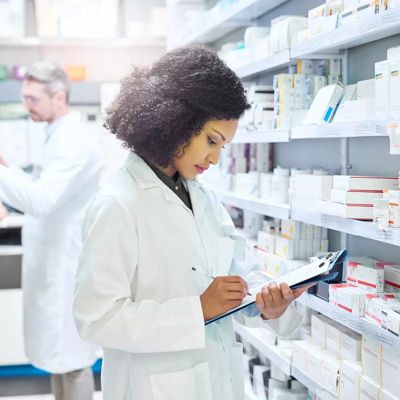 Female and male pharmacist working in an aisle in a pharmacy.