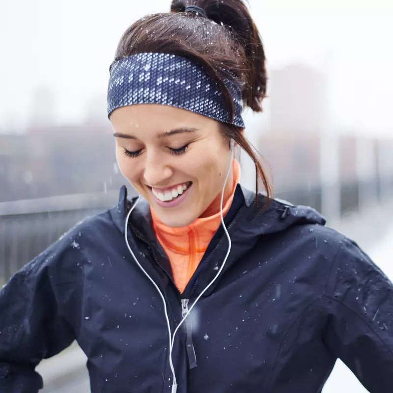 A woman runs in cold, wet weather.