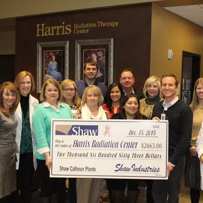 A group of co-workers standing next to each other while holding a big check.