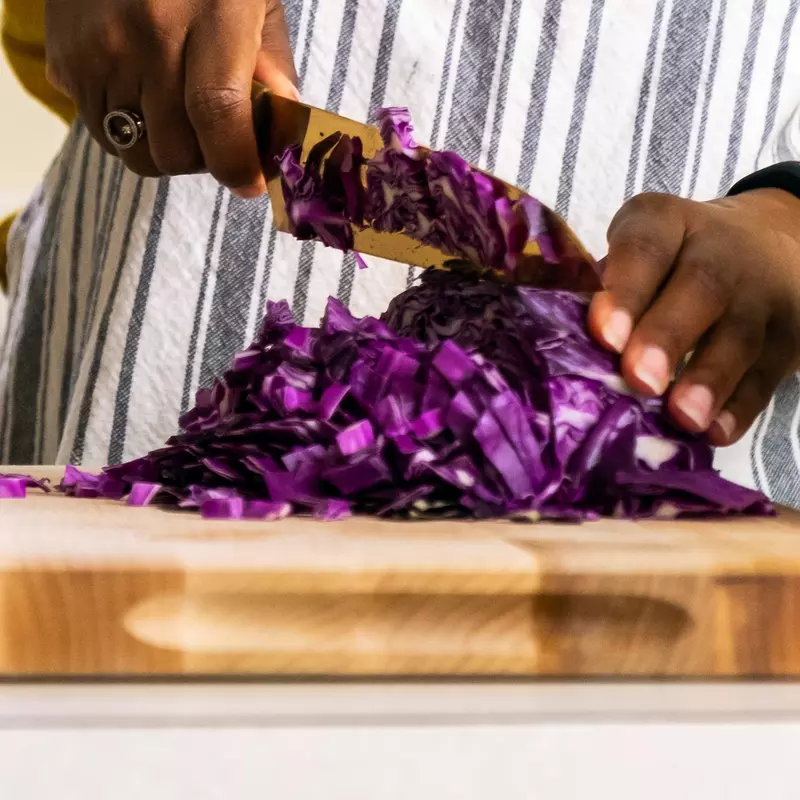A woman chopping purple cabbage.