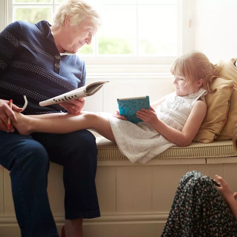 A woman doing a crossword with her grandchildren.