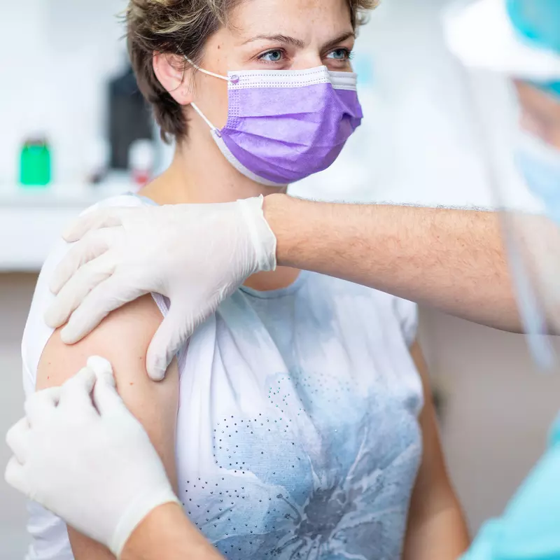 A doctor cleaning a woman's arm before he gives her a shot