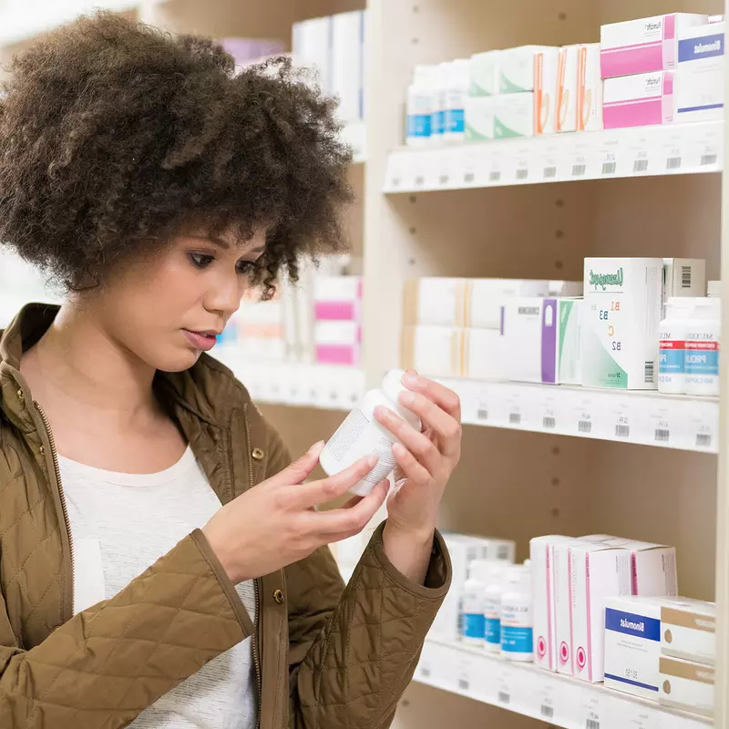A young woman analyzing an over-the-counter medication.