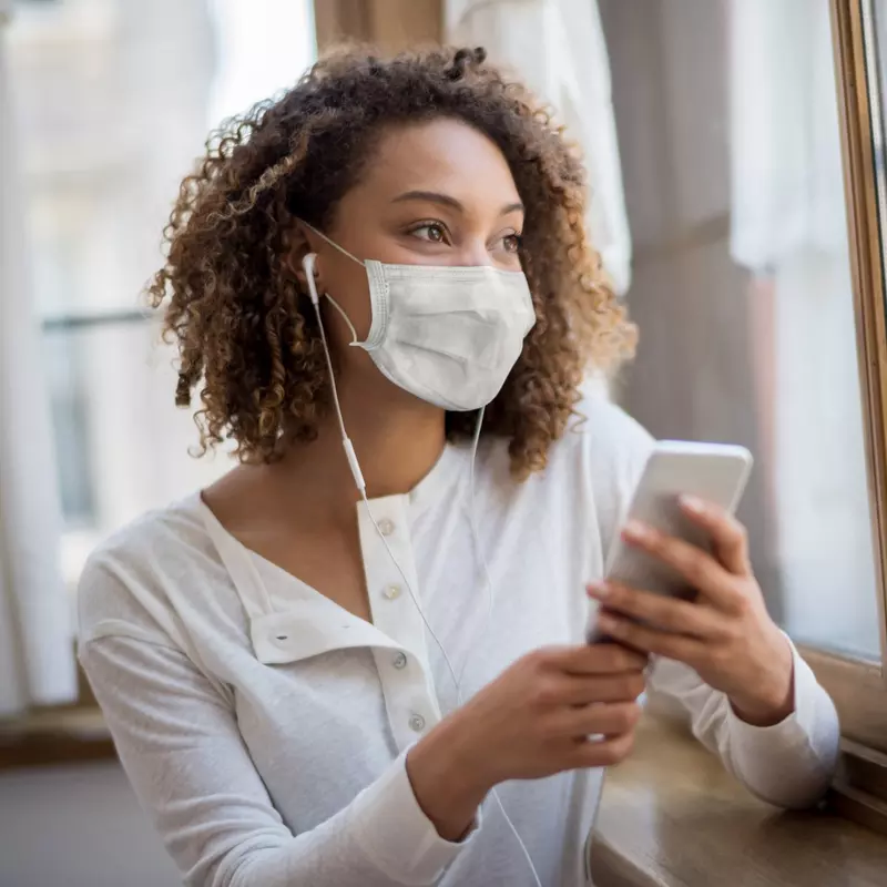 A woman wearing  face mask and using her cell phone. 