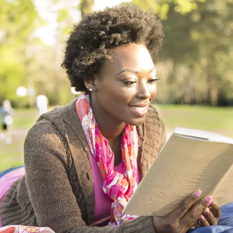 A woman reading a book outdoors.