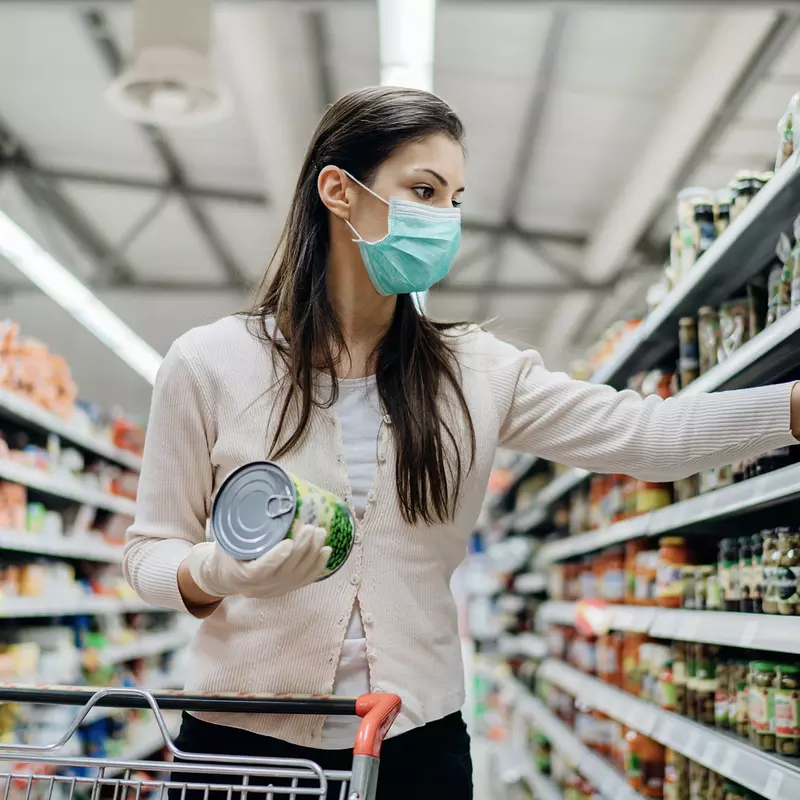 A woman shopping at the grocery store wearing a mask.