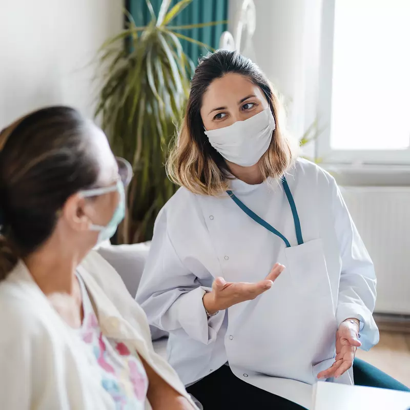 A woman speaking with her doctor wearing a mask.