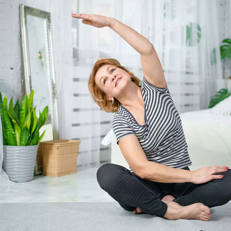 A woman stretching in her bedroom. 