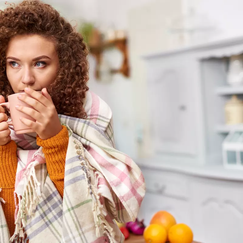 A woman sipping on her cup of coffee in her kitchen