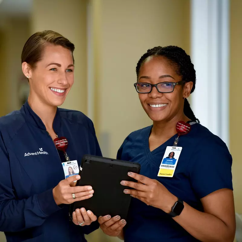 Two nurses from AdventHealth holding a tablet