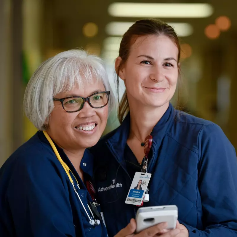 Two nurses from AdventHealth Palm Coast, smiling and looking to the right of the camera