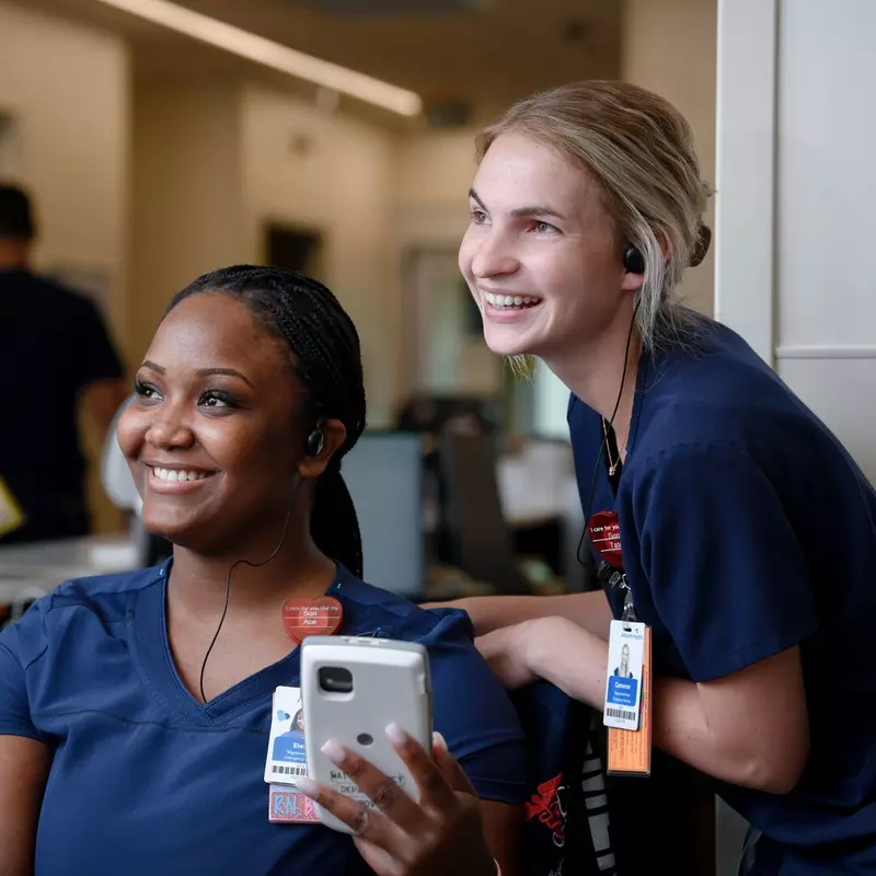 Two nurses from AdventHealth, smiling and looking to the left. 
