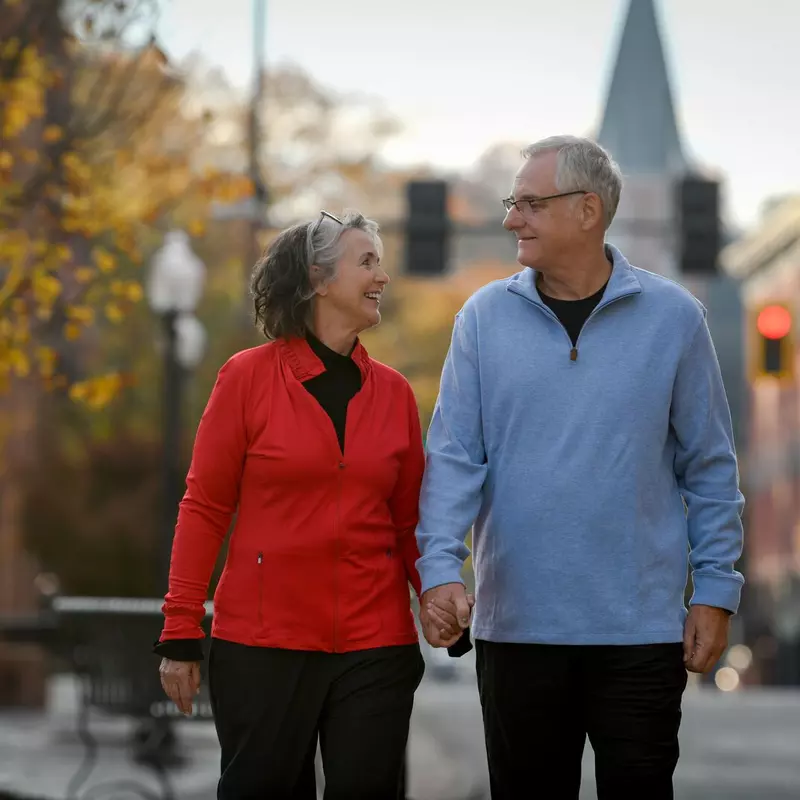 Older couple walking down sidewalk.