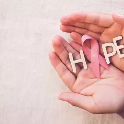 Hands holding a pink ribbon and the word hope.