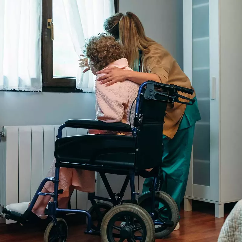 Woman embracing elderly woman in hospice/home care