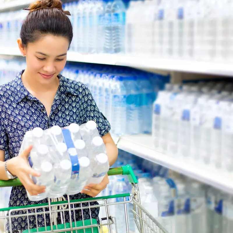 Woman stocking up on bottled water at the grocery store.