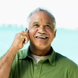 Mature man talking on phone while wearing invisible hearing aid