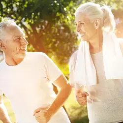 An older couple goes jogging outdoors.