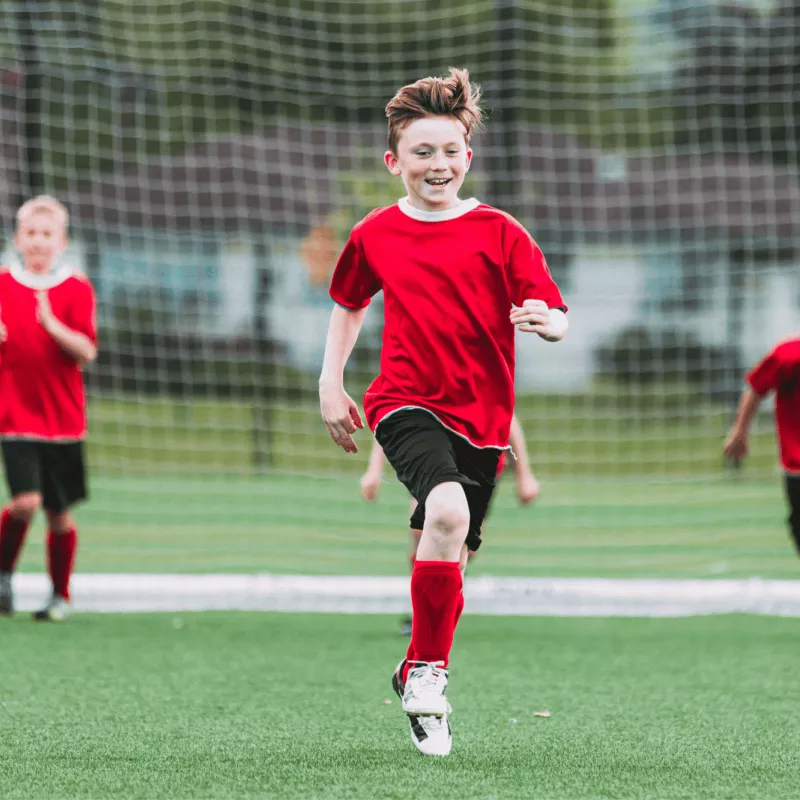 A group of kids in uniforms playing soccer.