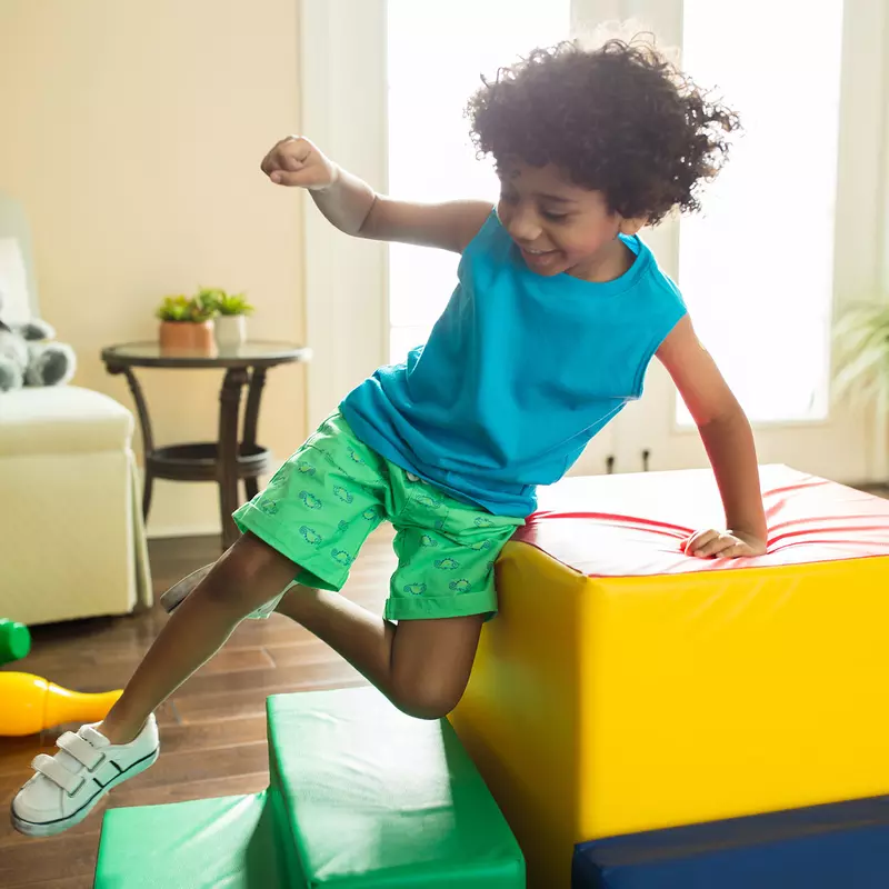 A little boy jumping in the family room.