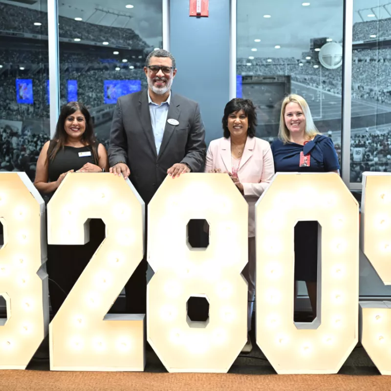 Representatives from United Against Poverty, Lift Orlando, AdventHealth for Children and KPMG stand behind a lighted 32805 sign.