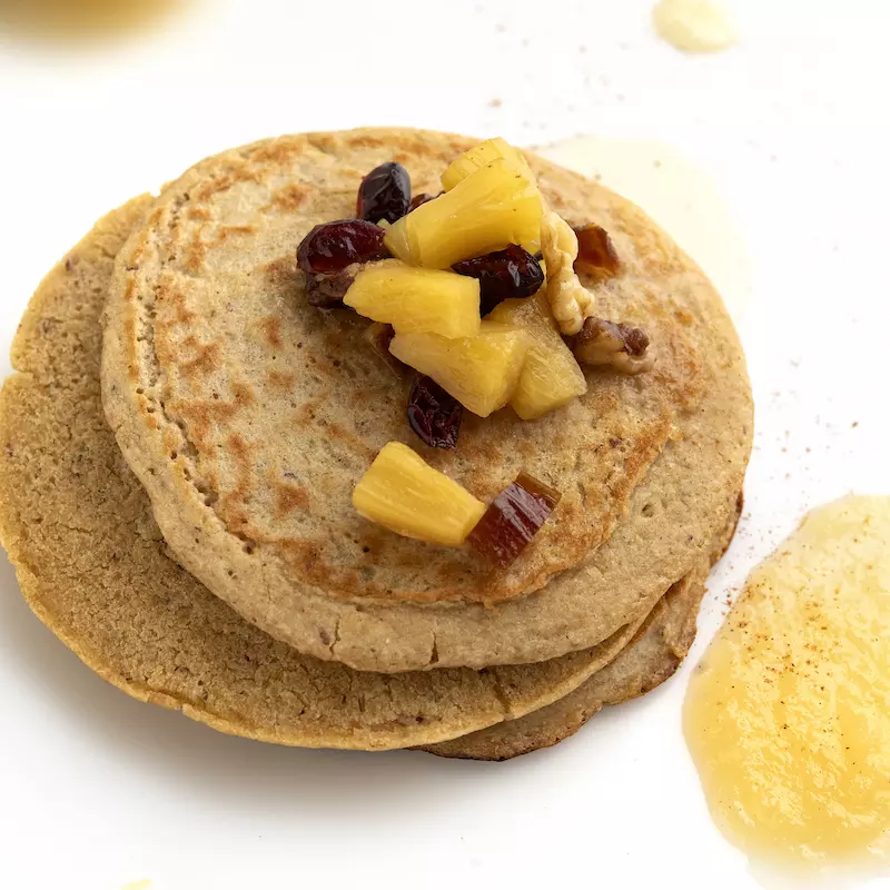 Stack of whole wheat pancakes with fruit and applesauce garnish