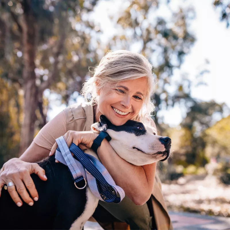 A middle aged woman hugging a dog.